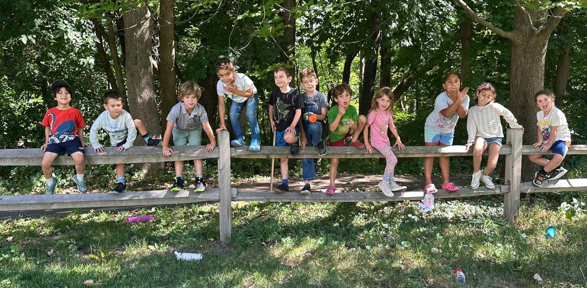 A group shot of the Primary 1 students standing on a fence.